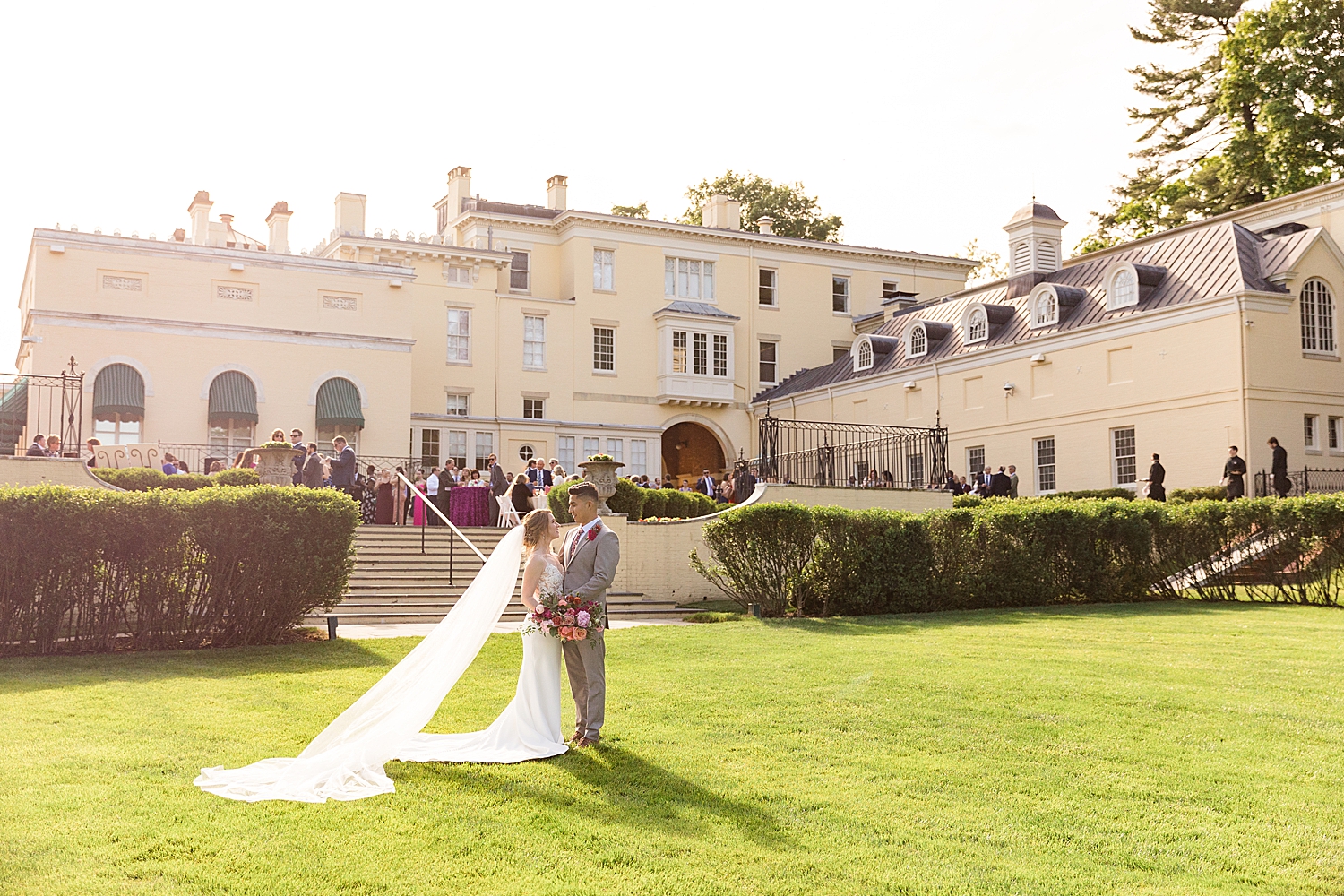 bride and groom walk the lawn in front of evergreen museum baltimore