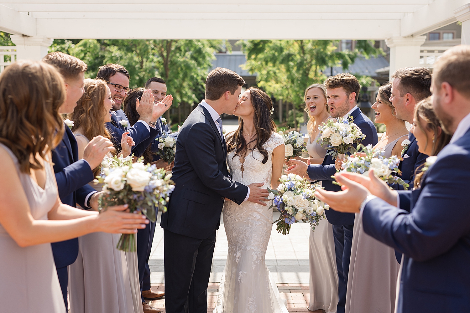 couple kiss while wedding party cheers