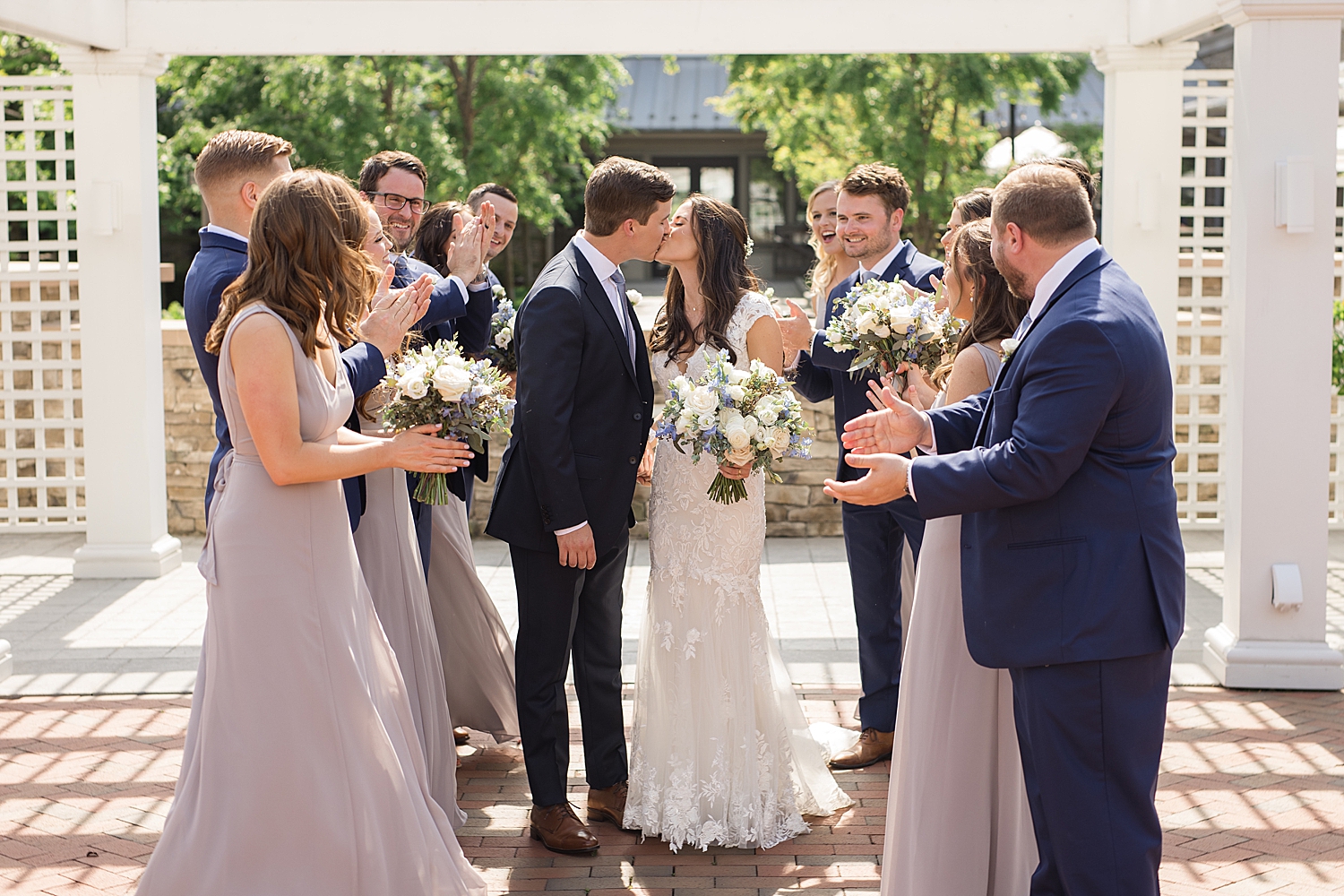 couple kiss while wedding party cheers