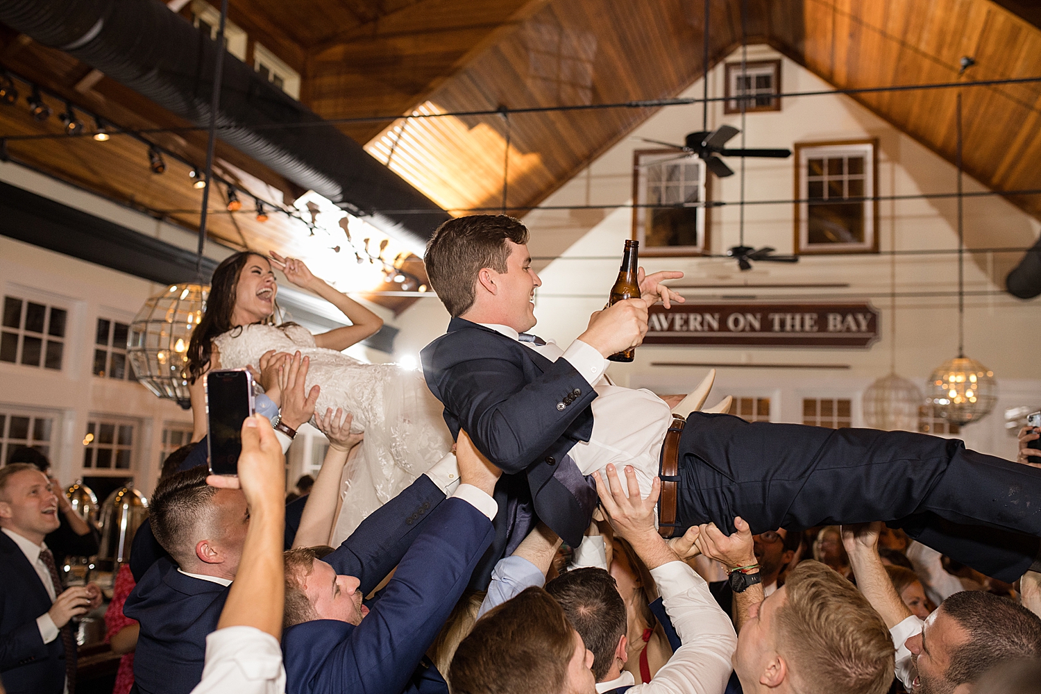 bride and groom crowd surf held up by wedding guests