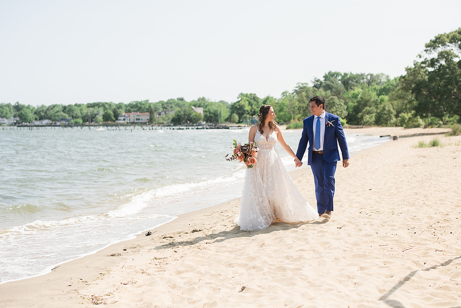 bride and groom walking hand in hand along beach