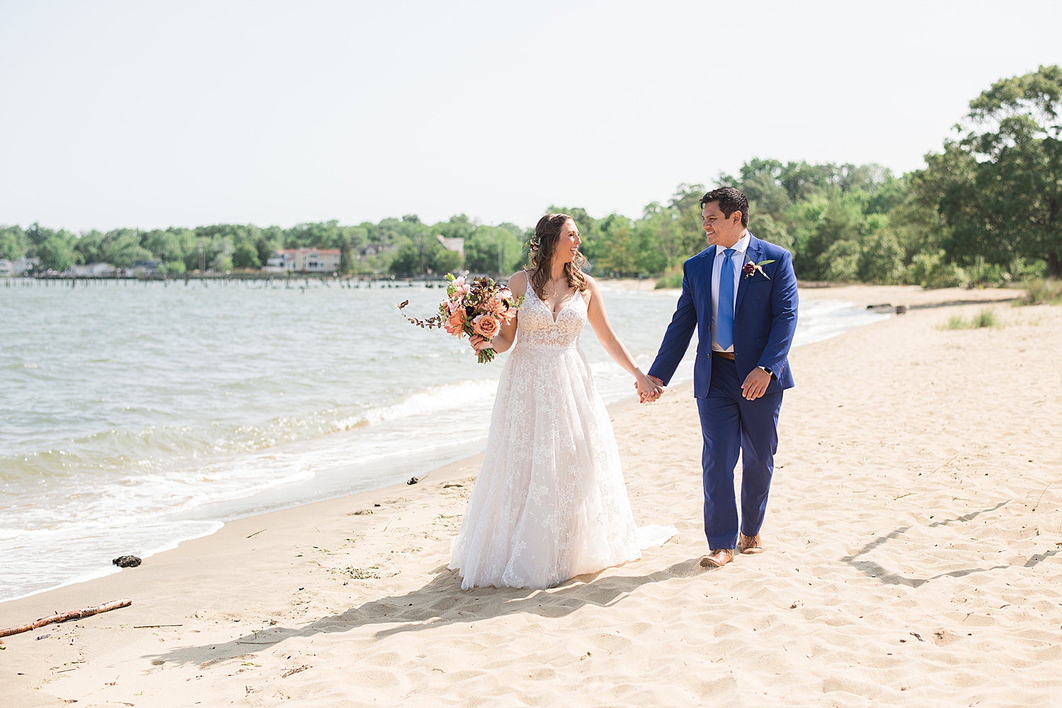 bride and groom walking hand in hand along beach