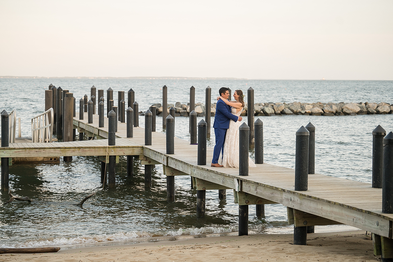 bride and groom embrace on pier