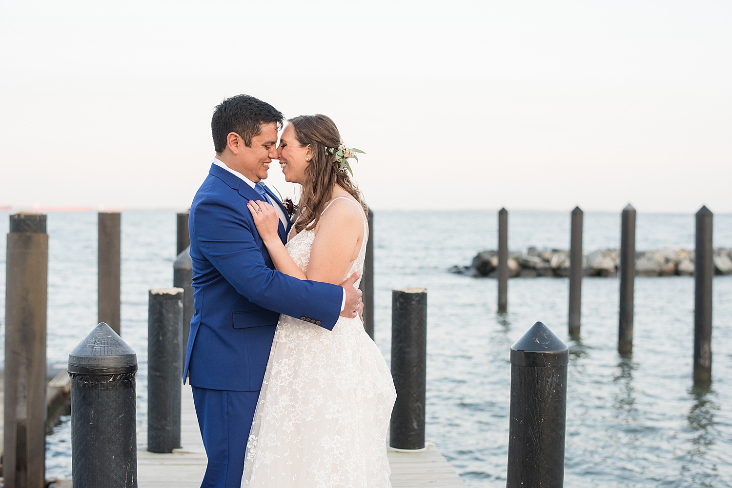 bride and groom embrace on pier