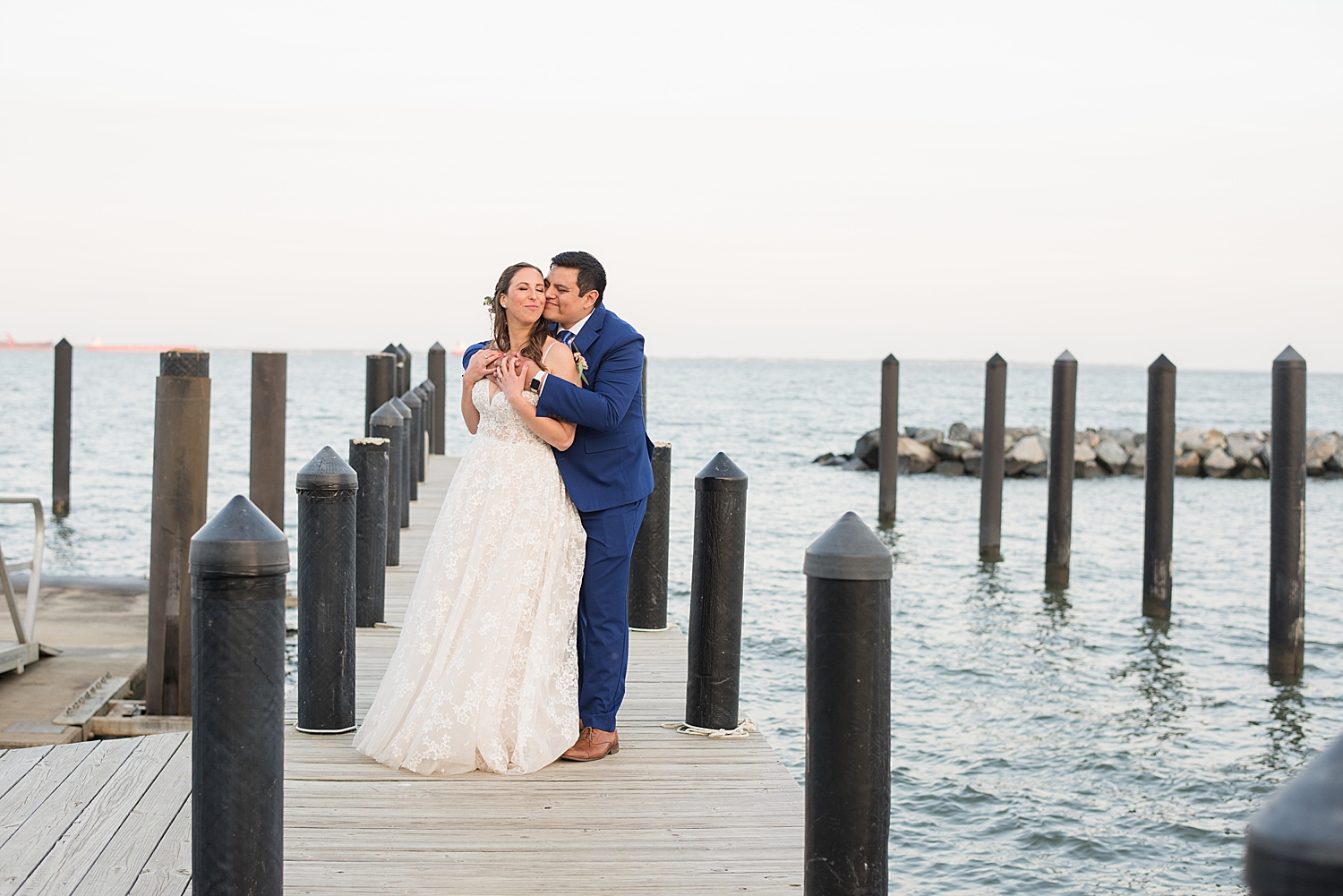 bride and groom embrace on pier