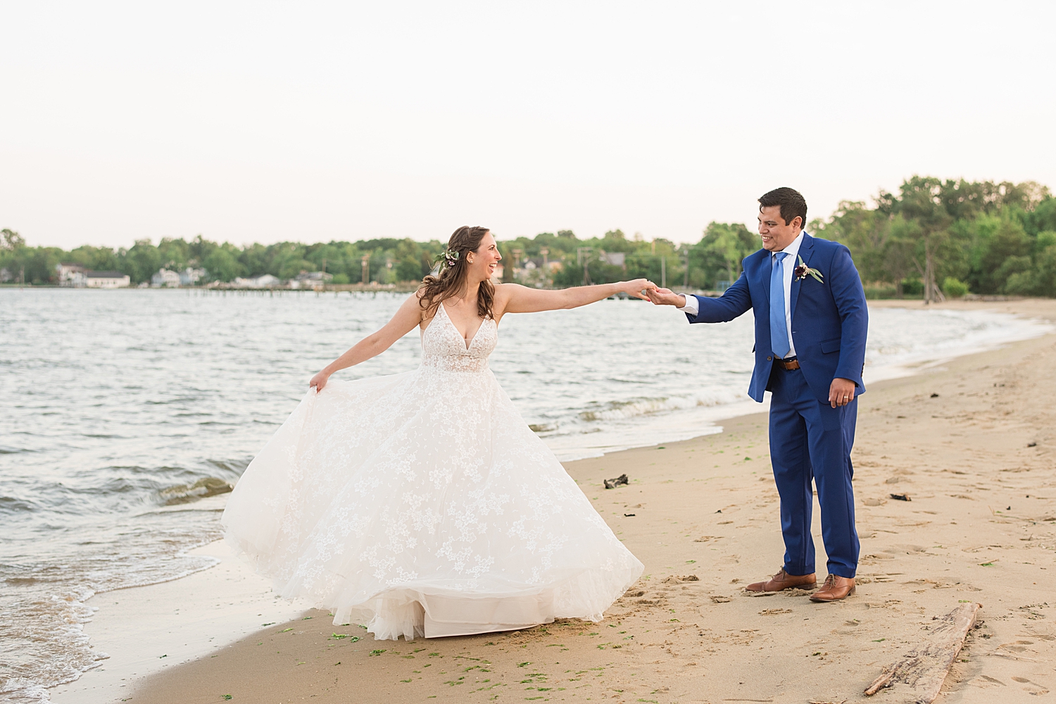 groom spins bride on beach by the water