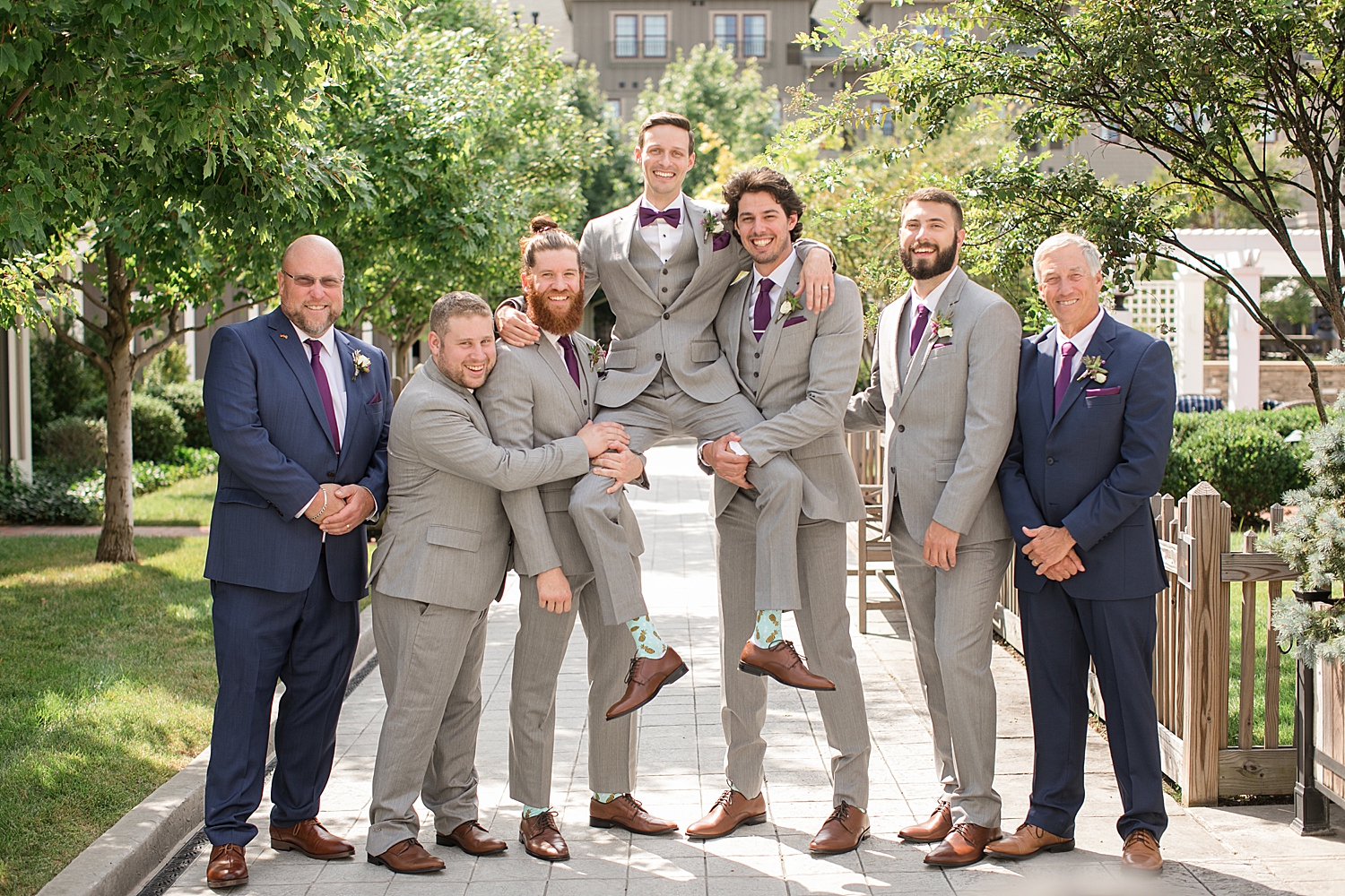 groomsmen holding groom up and smiling at camera