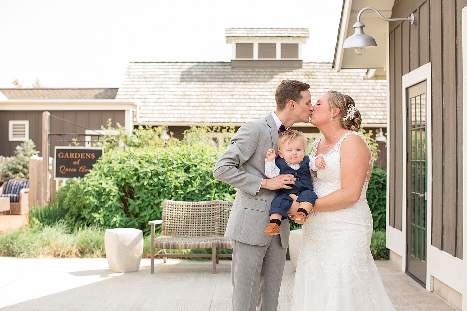 bride and groom kiss while holding their son