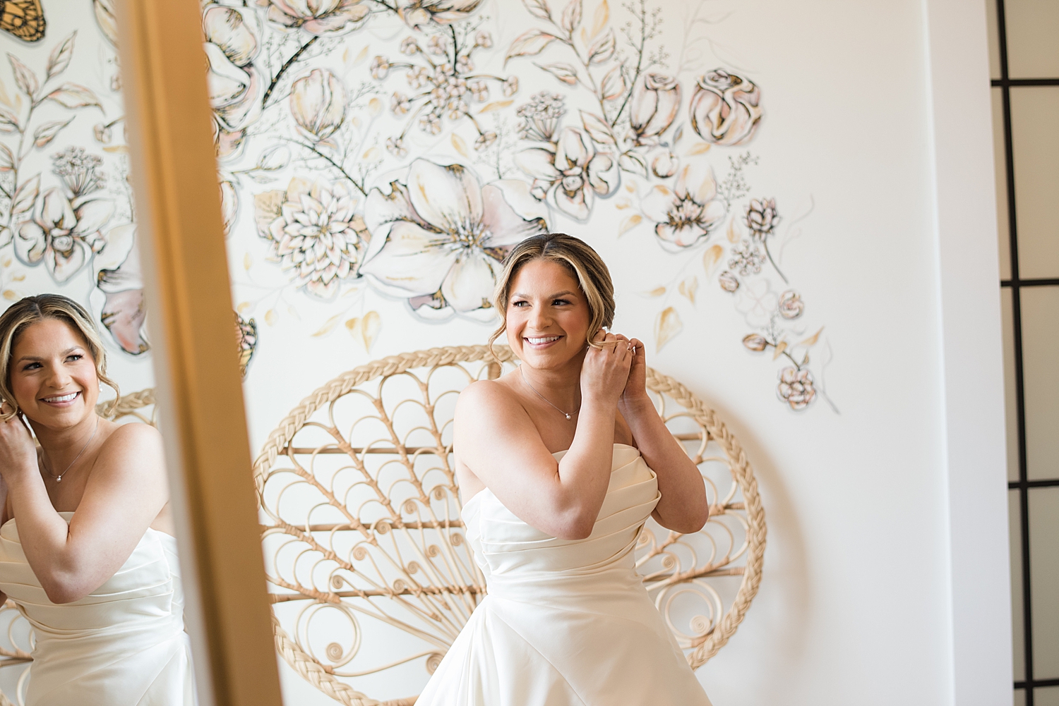 bride putting in earrings in wedding gown