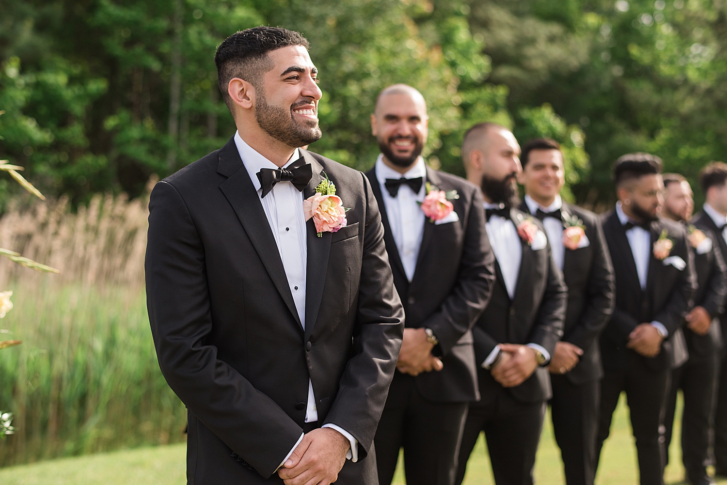 groom smiling, waiting for bride at the end of the aisle