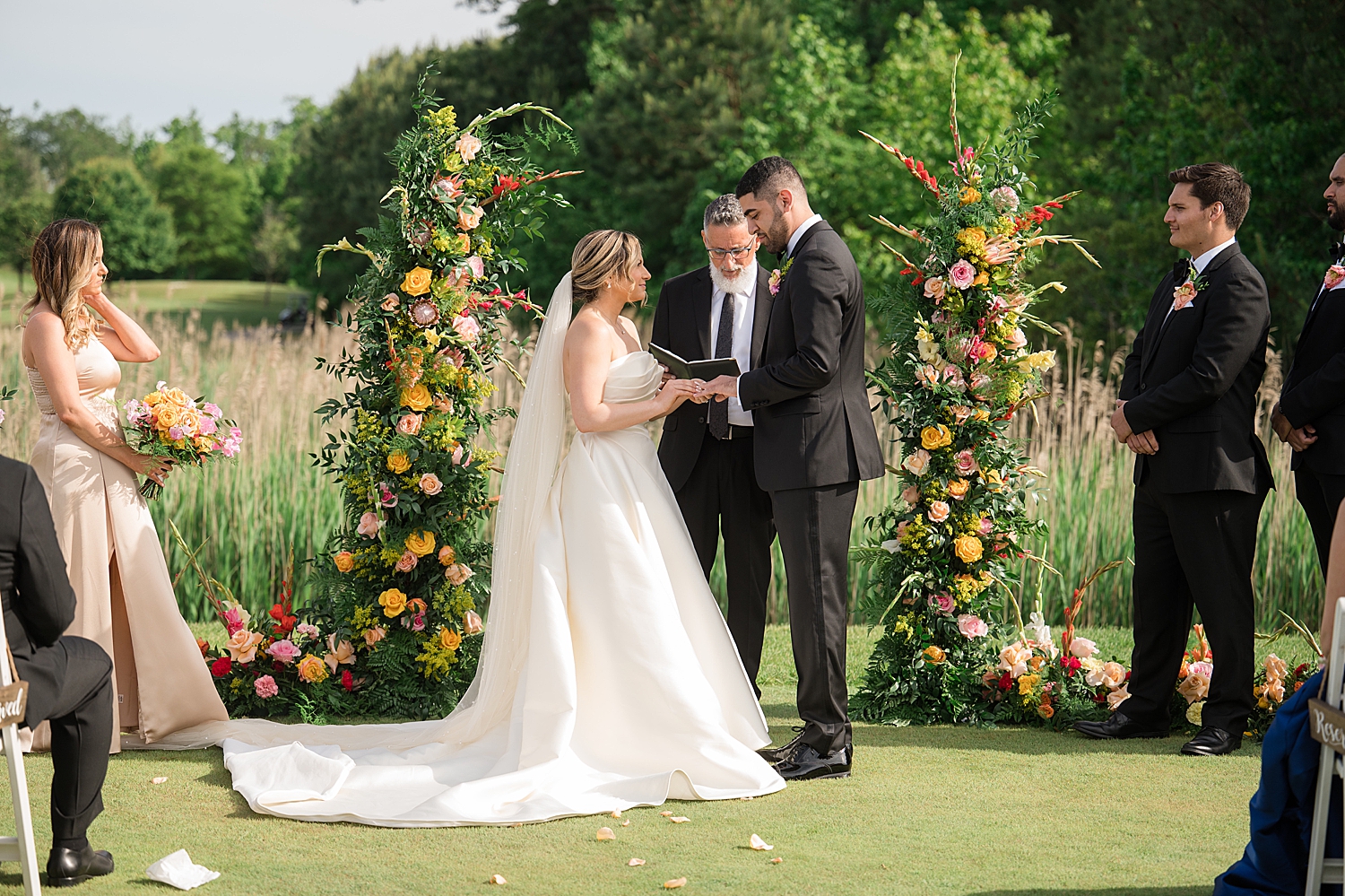 ceremony outdoors in green field floral pillars