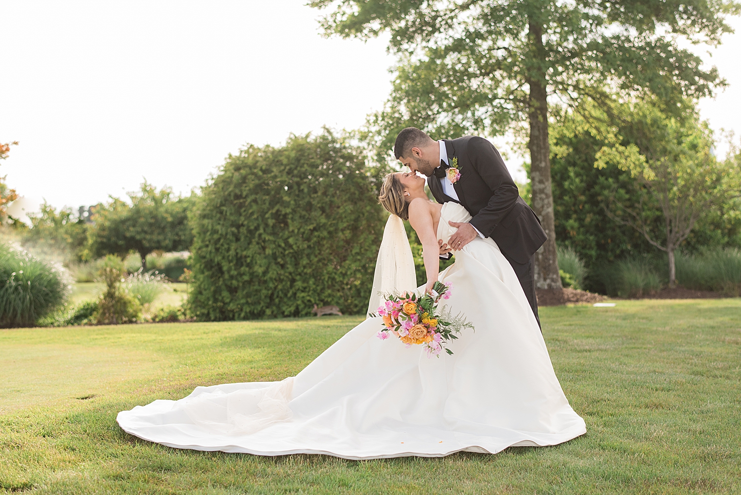 bride and groom couple portrait in grass, dip kiss