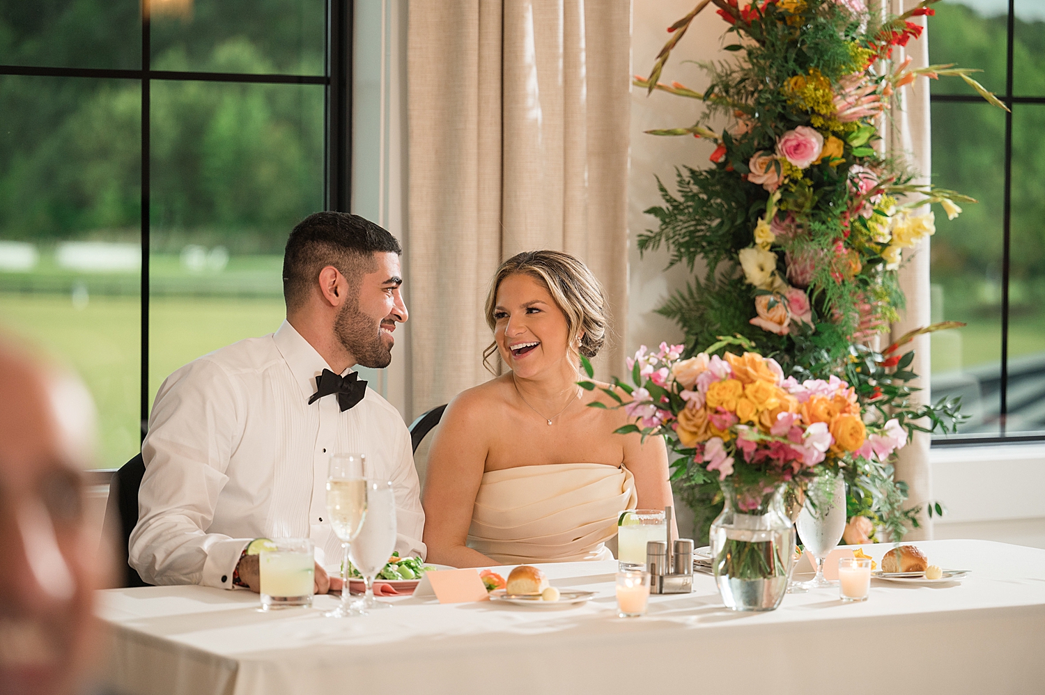 bride and groom reacting to wedding toasts from head table