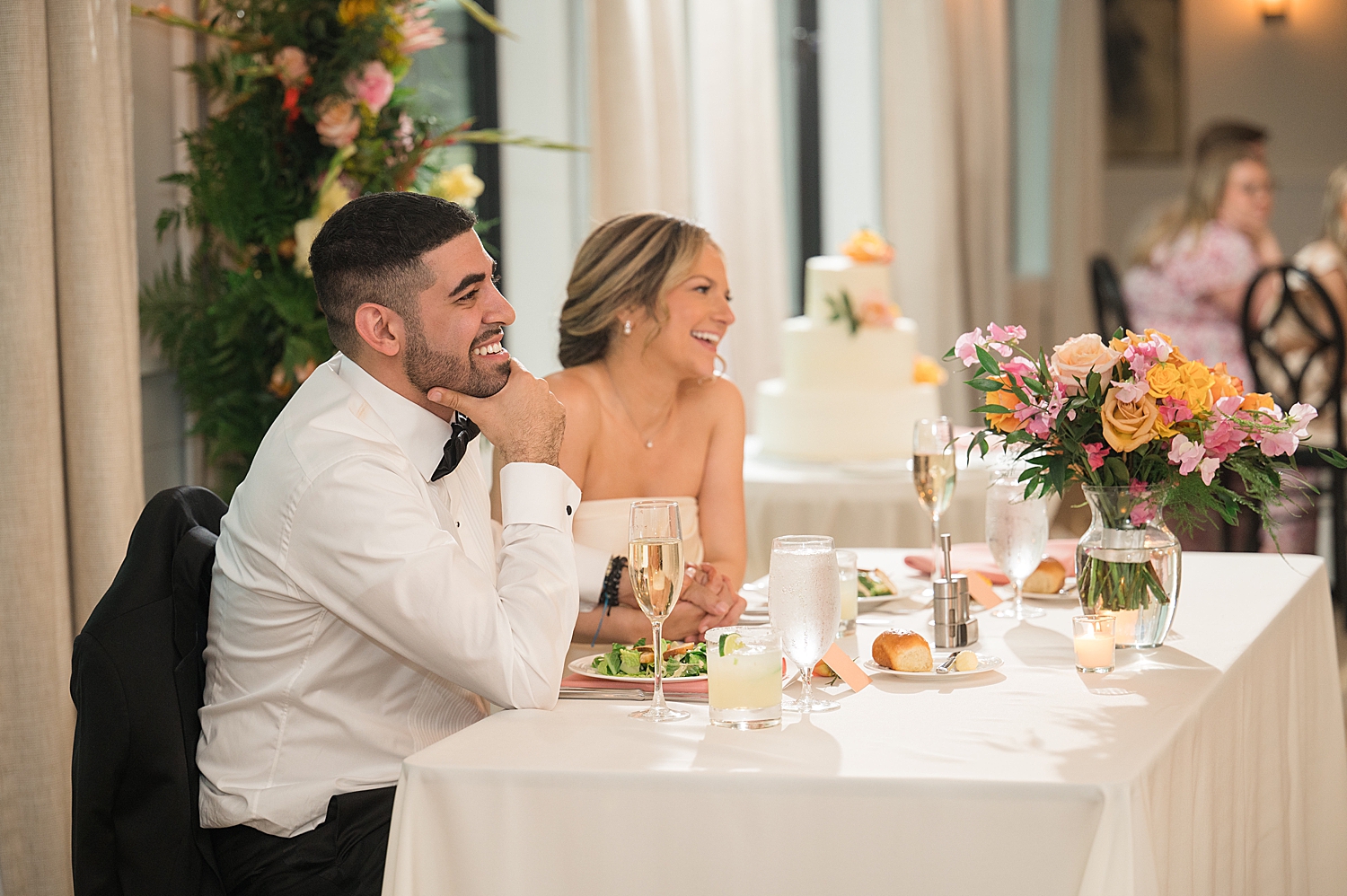 bride and groom reacting to wedding toasts from head table