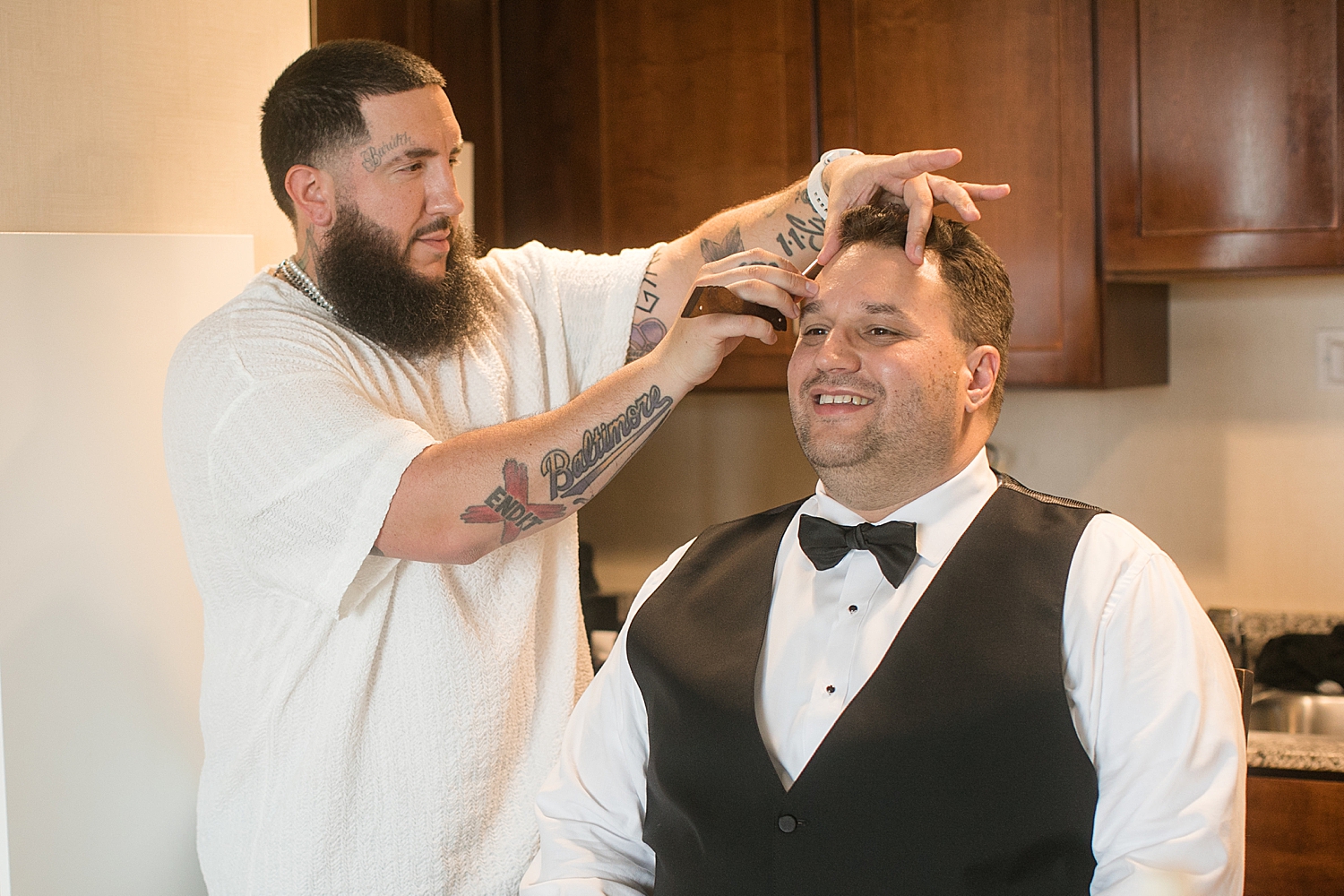 groom getting eyebrows shaped by tattooed barber