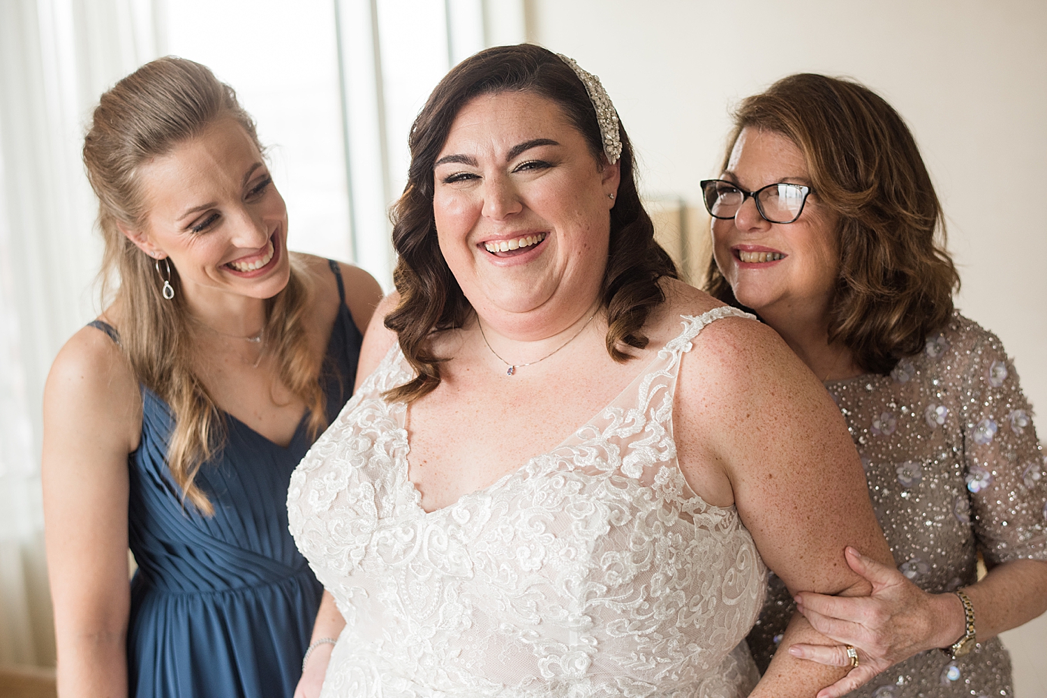 bride laughing with mom and sister after getting dressed