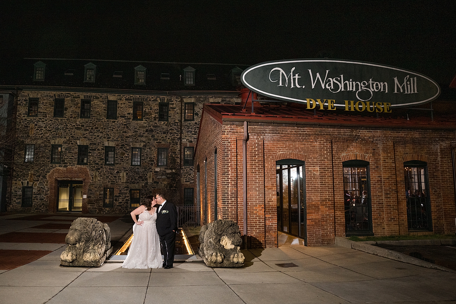 bride and groom portrait in front of venue at night