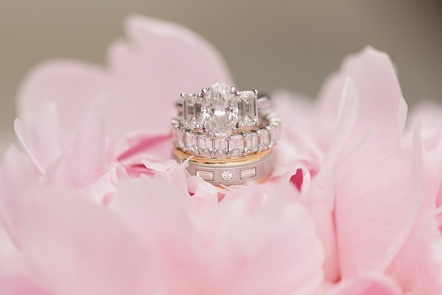 silver wedding rings stacked on pink flower petals