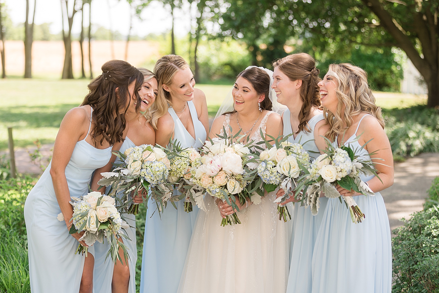 bride laughing with bridesmaids in light blue dresses