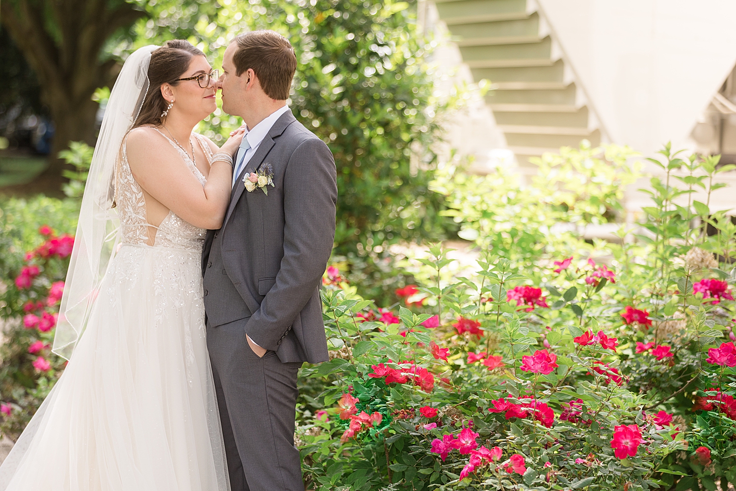 bride and groom embrace in front of rose bush