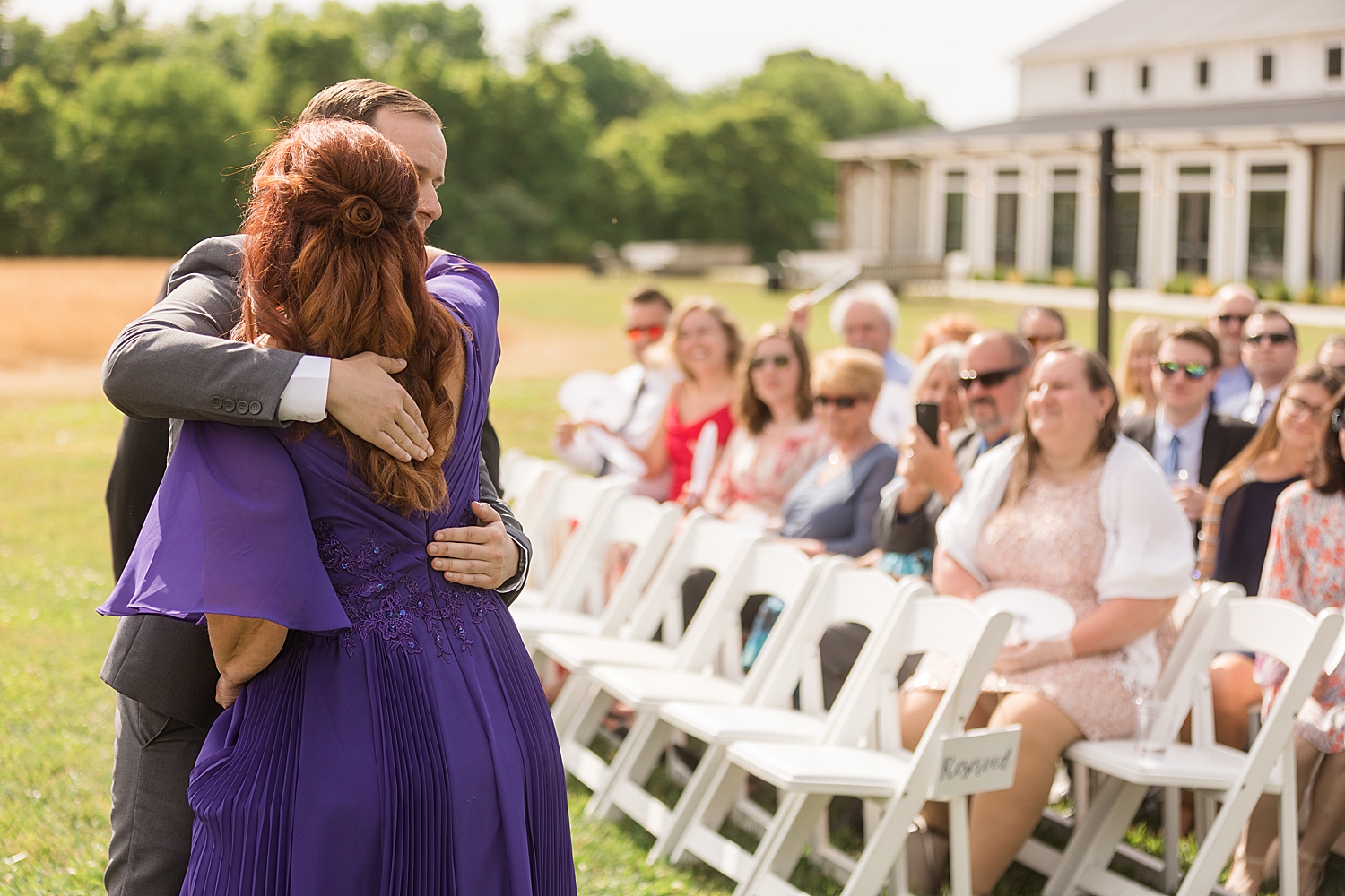 groom hugs mom at end of aisle