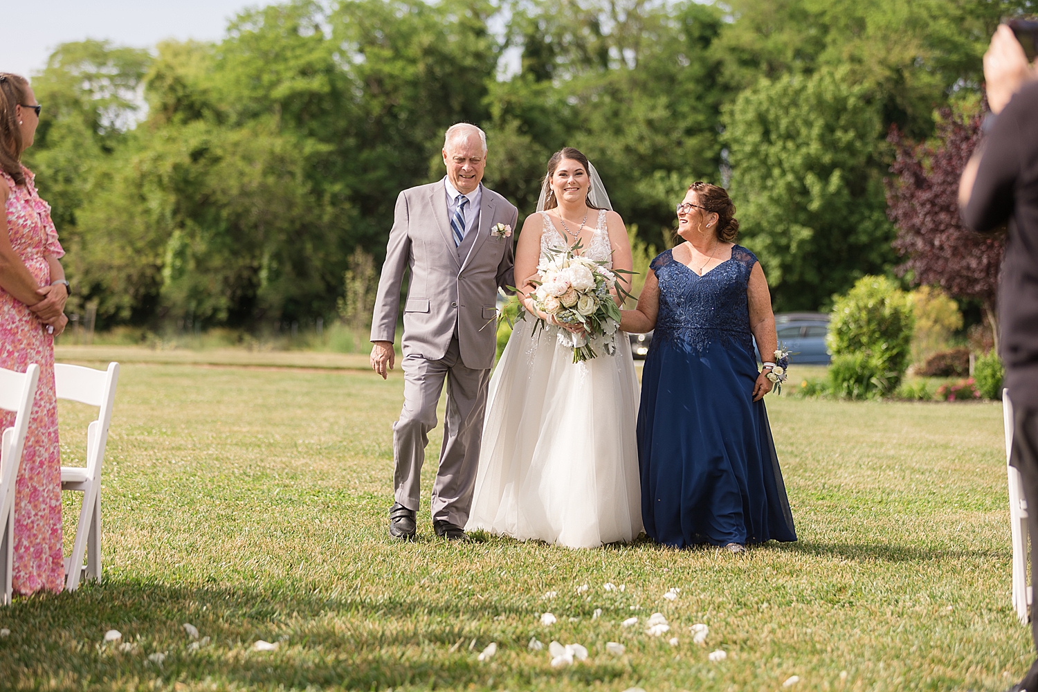 bride walks with parents down the ceremony aisle