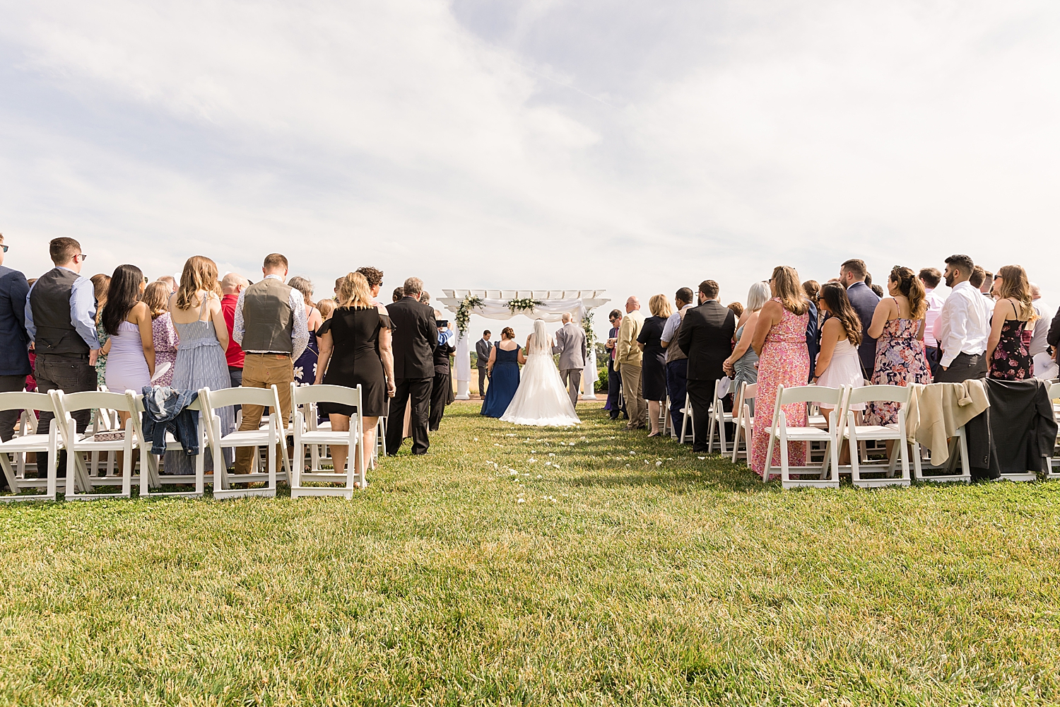 bride walks with parents down the ceremony aisle