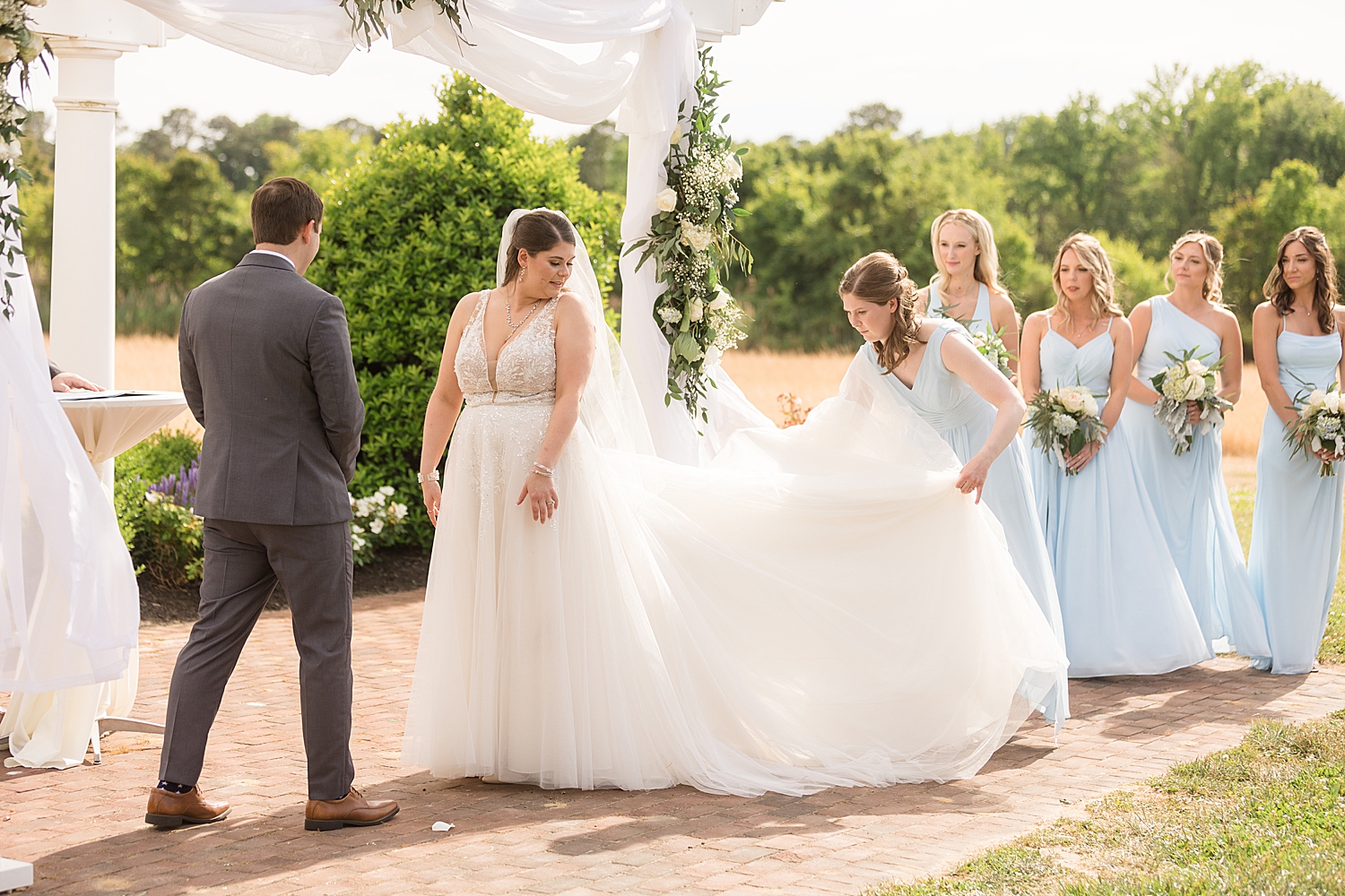 maid of honor fluffs bride's dress at the end of the aisle