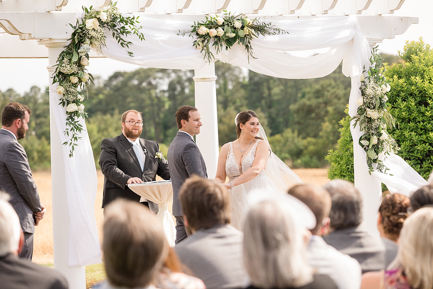 bride and groom look out at guests during ceremony