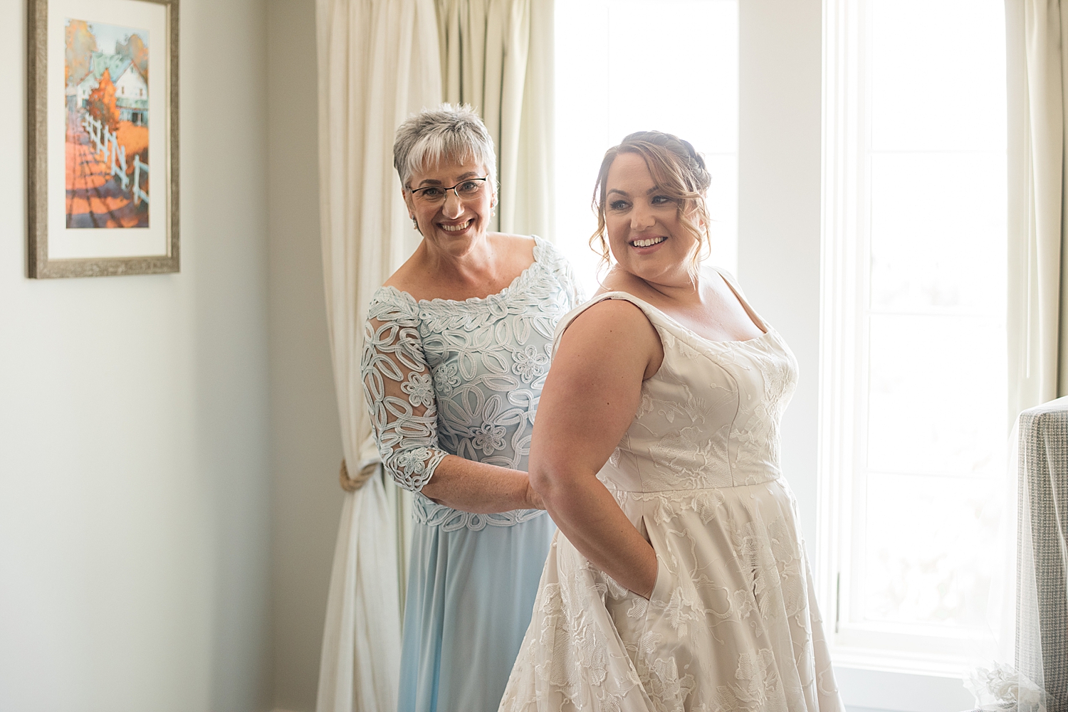 bride's mom helps her get dressed