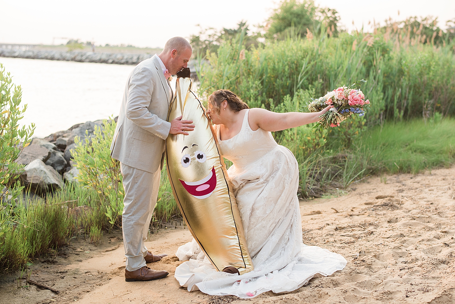  couple portrait on beach, bride kisses inflatable gold banana