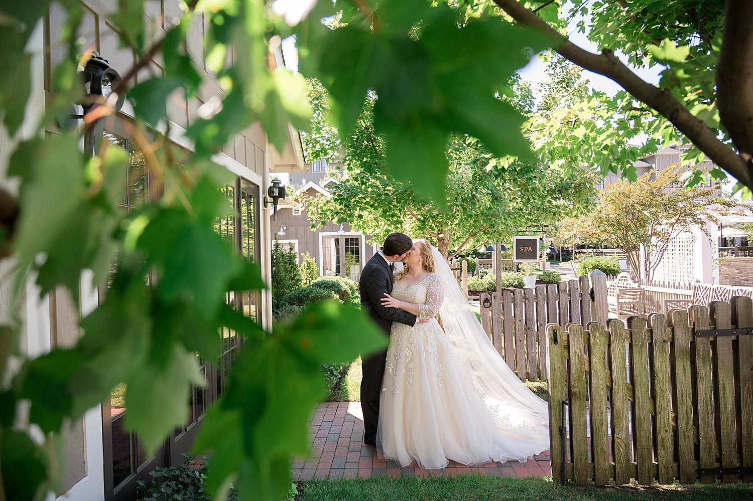 bride and groom portrait under trees kiss