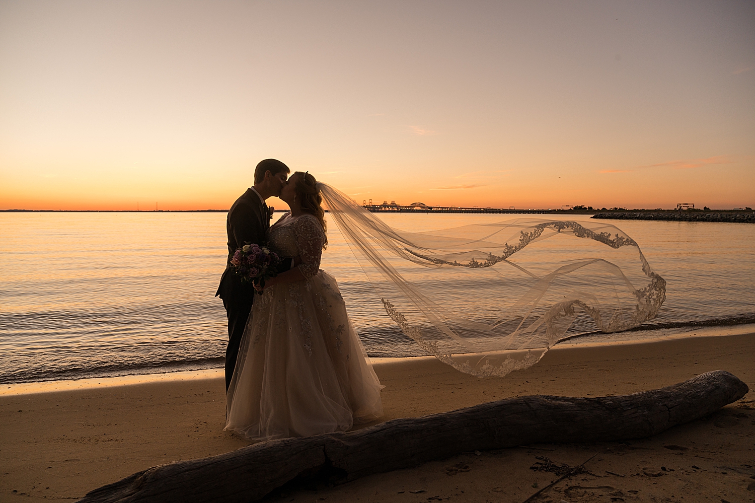 bride and groom portrait on beach at sunset veil toss