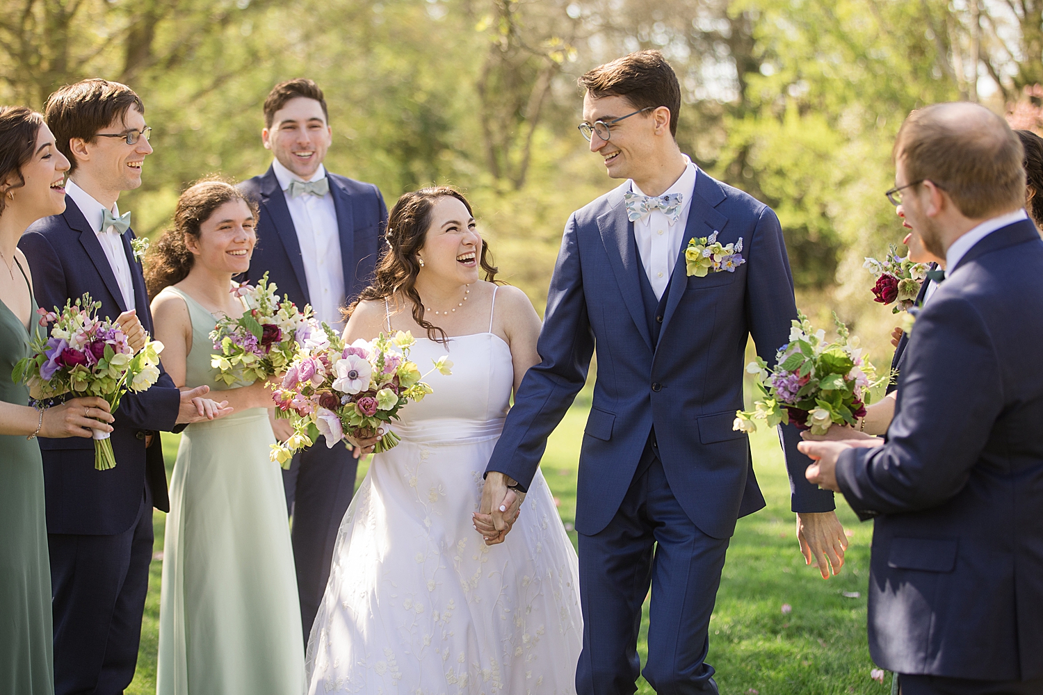 bride and groom smiling at each other with wedding party