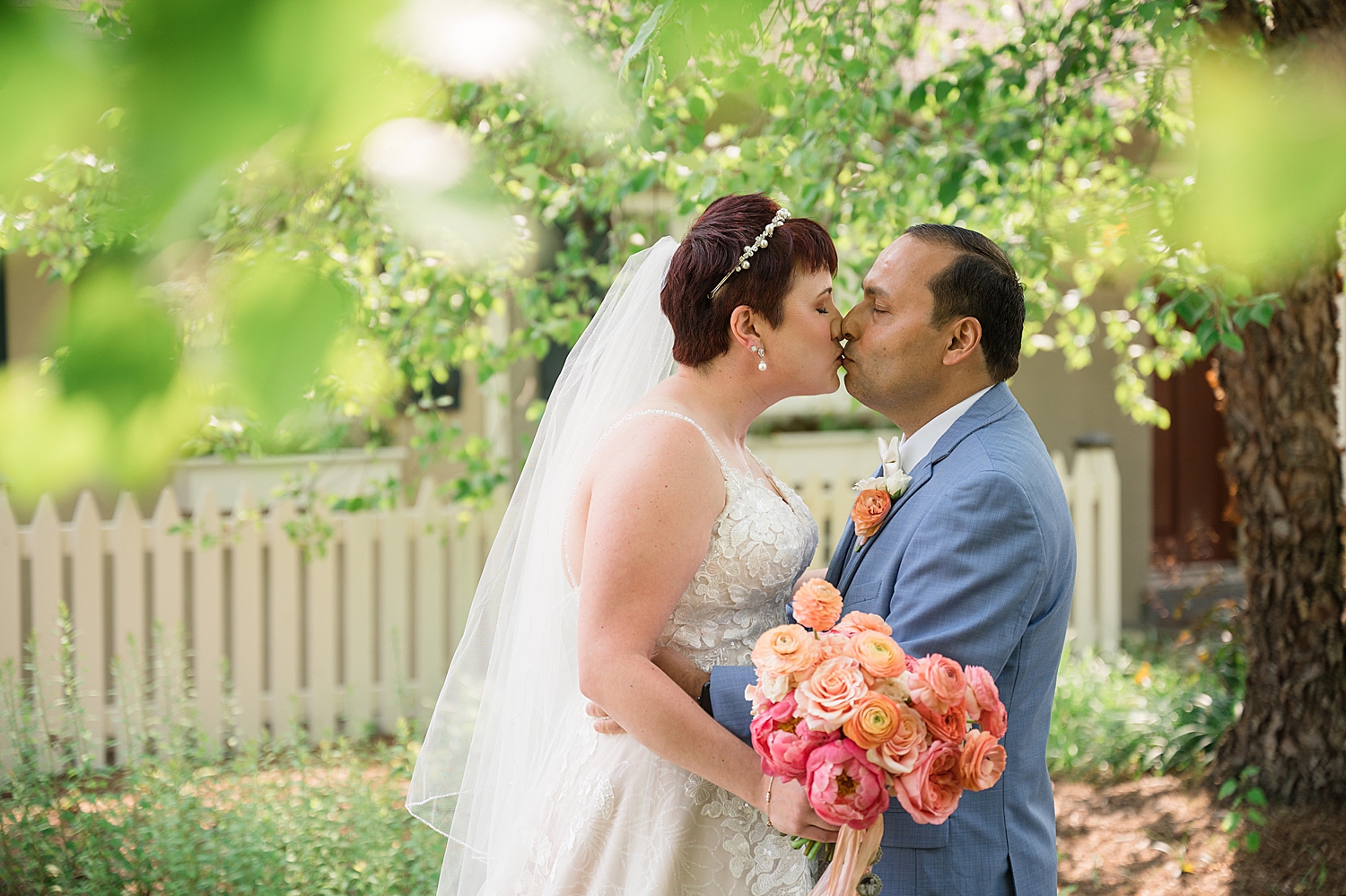 bride and groom portrait kiss, coral bouquet blue suit