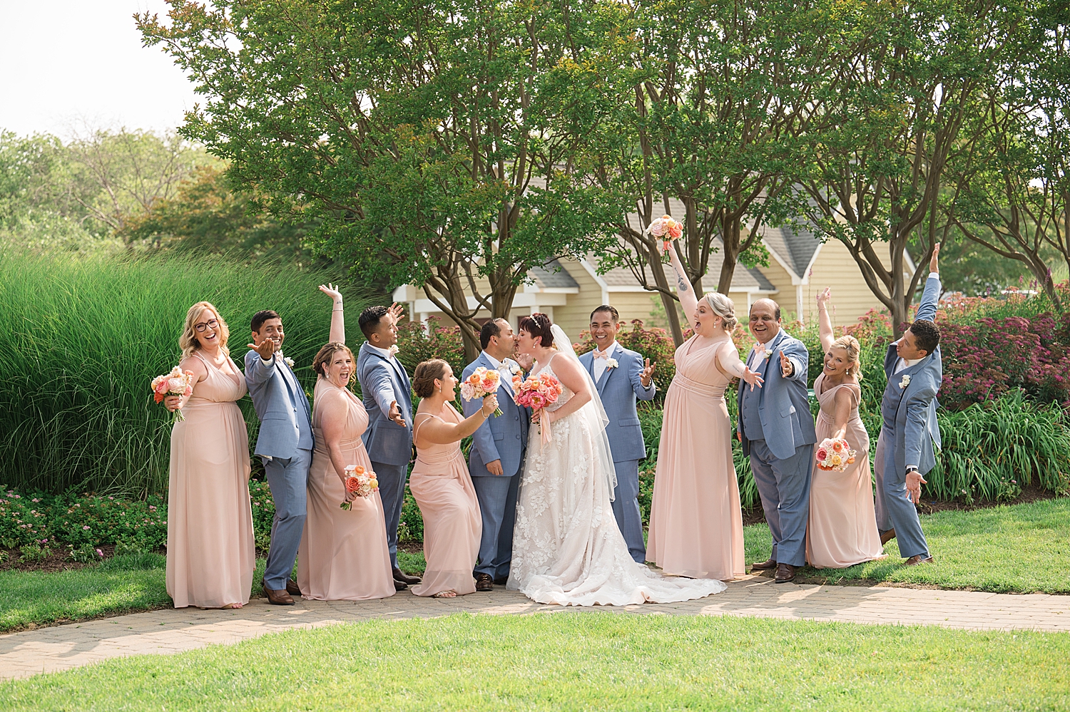 full wedding party cheering while couple kiss