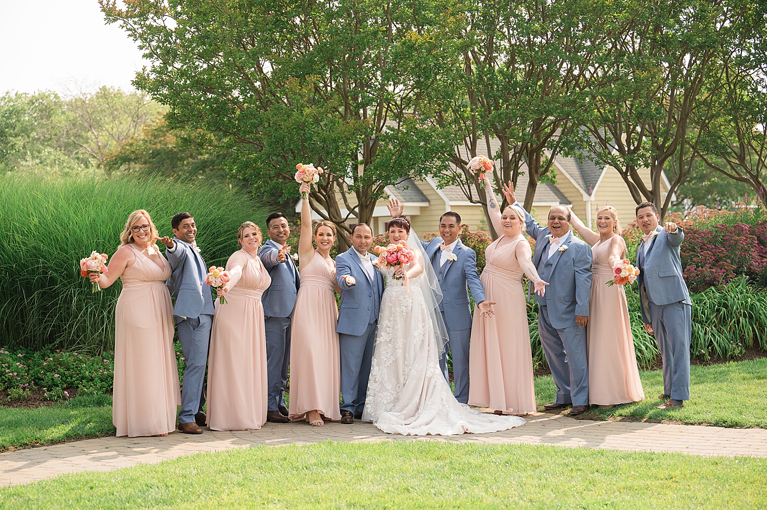 full wedding party cheering while couple kiss