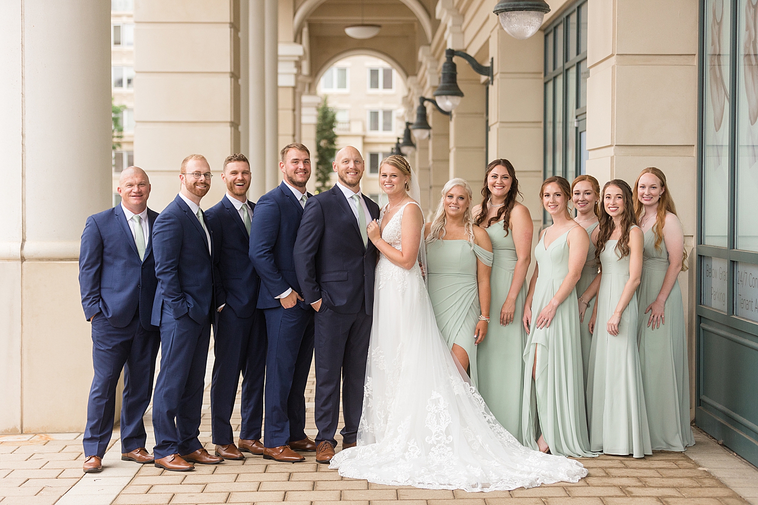 full wedding party photo, guys in navy, girls in sage