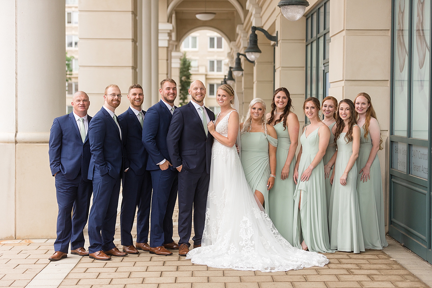 full wedding party photo, guys in navy, girls in sage