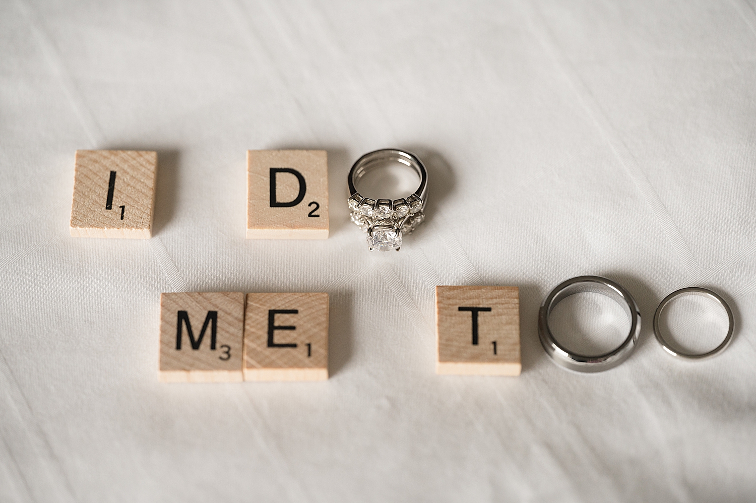 "i do me too" spelled in scrabble letters with wedding bands