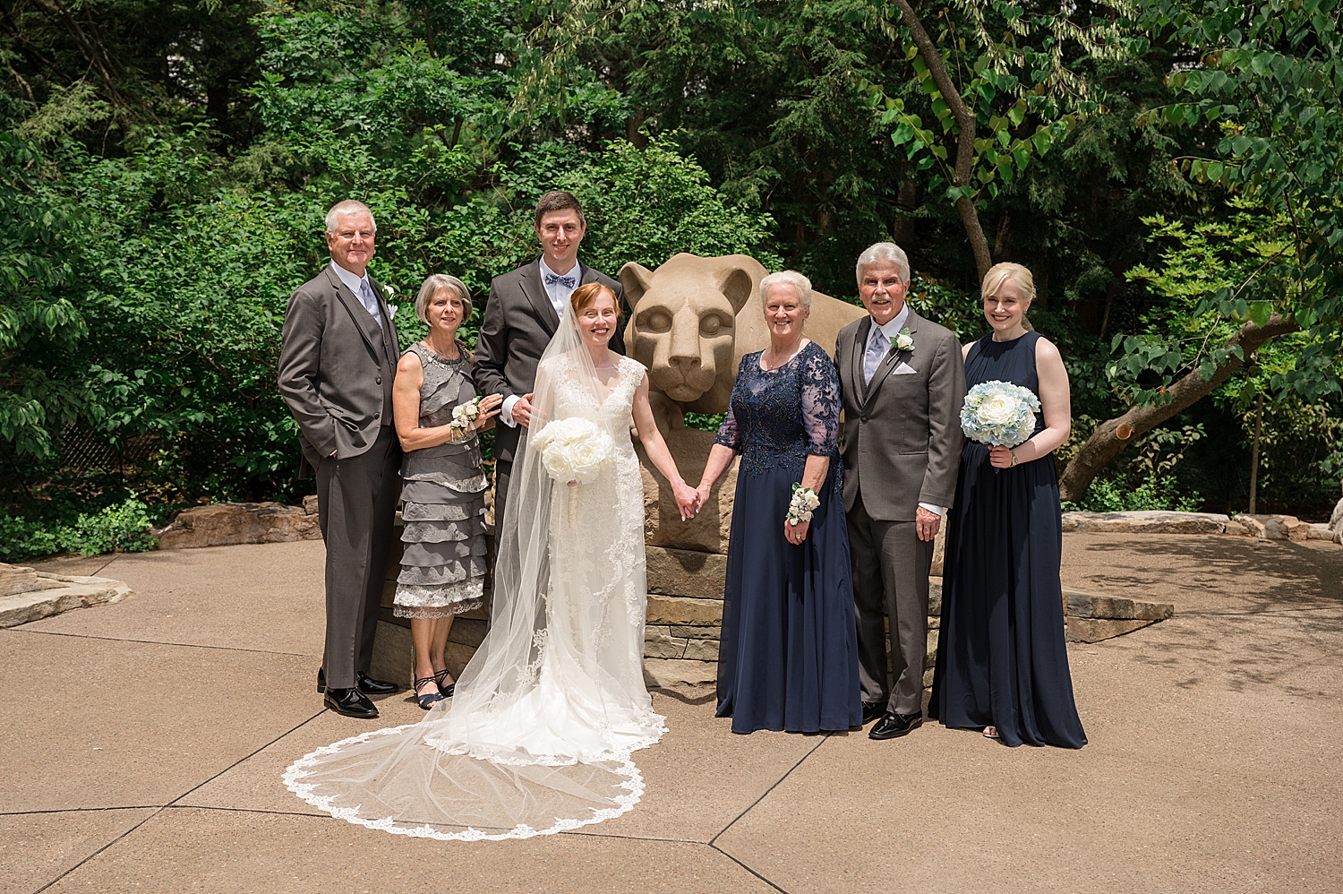 full wedding party posing with bride and groom and penn state lion