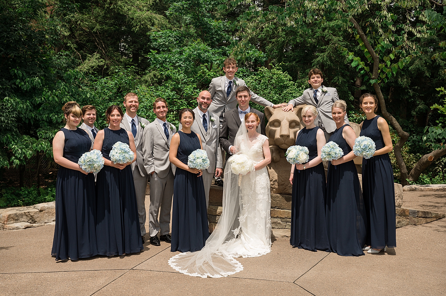 full wedding party cheering with bride and groom and penn state lion