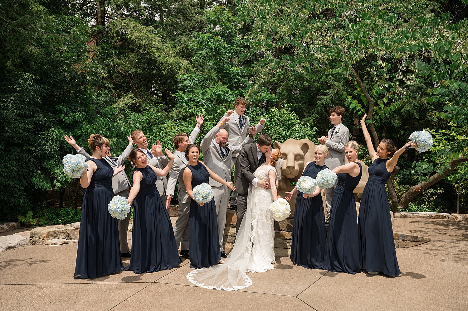 full wedding party cheering with bride and groom and penn state lion