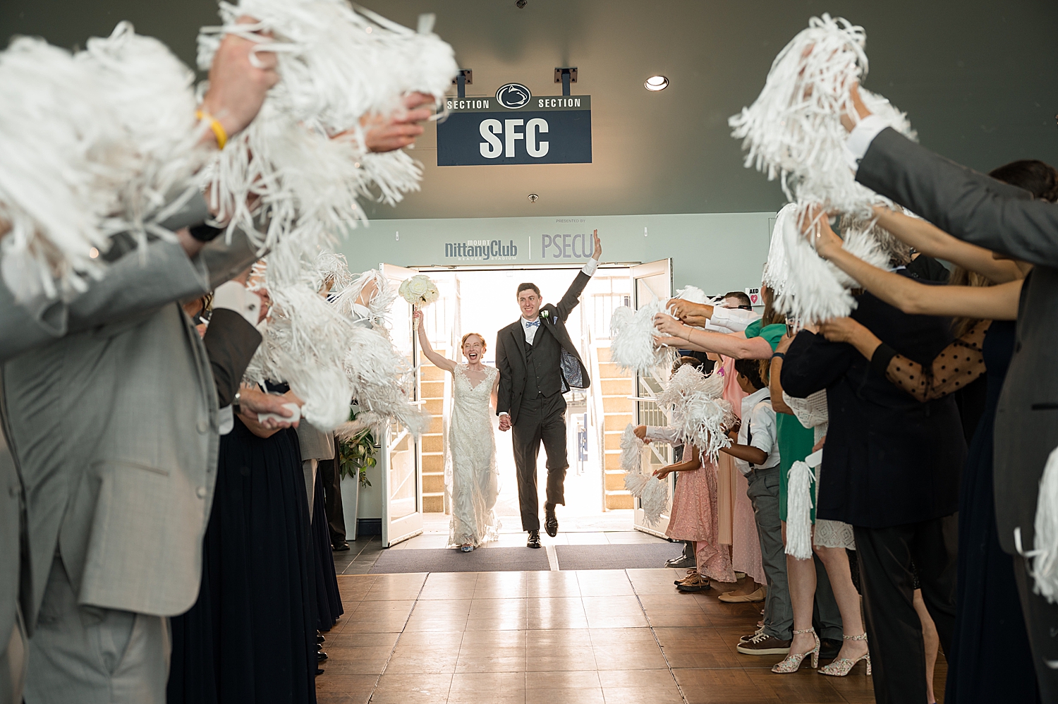 bride and groom enter tunnel with white pom poms