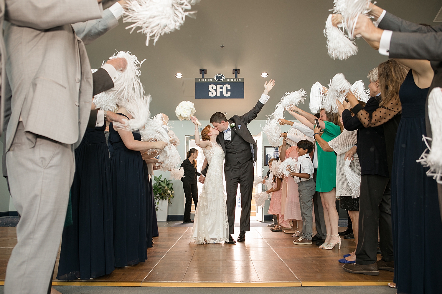 bride and groom enter tunnel with white pom poms