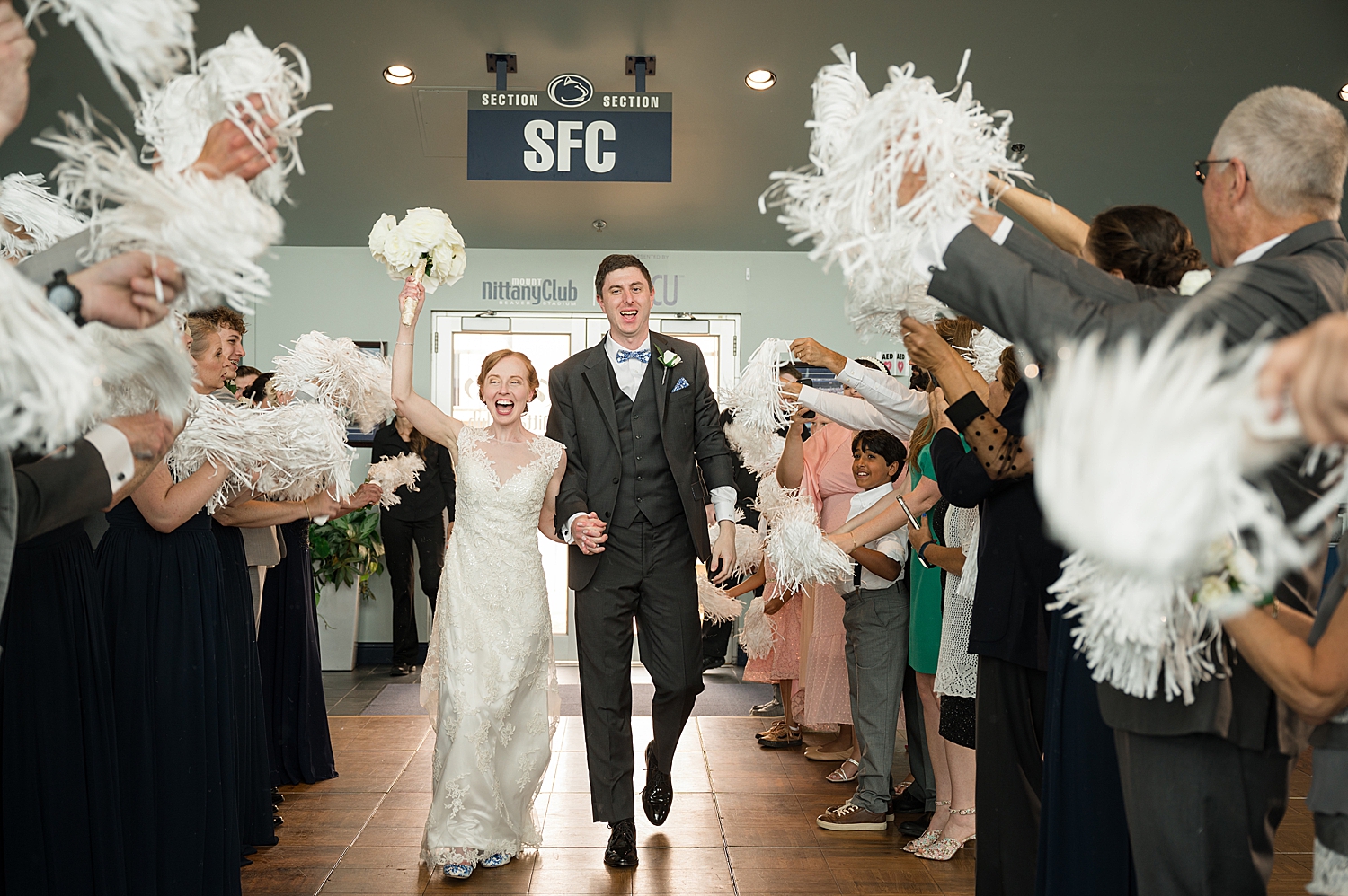 bride and groom enter tunnel with white pom poms