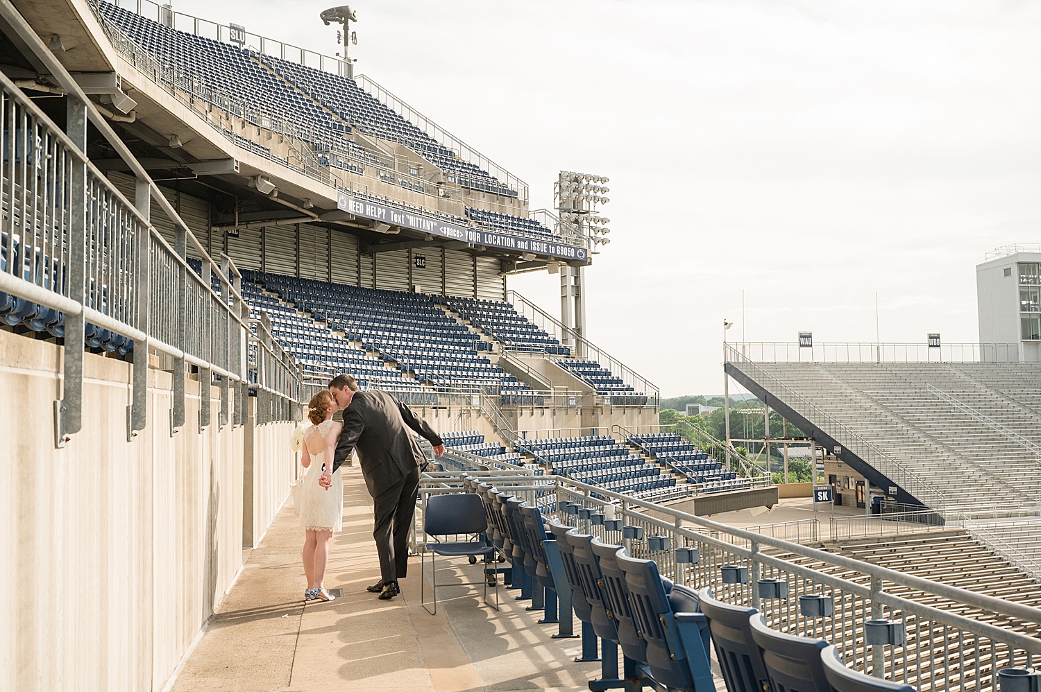 bride and groom kiss in stands at beaver stadium