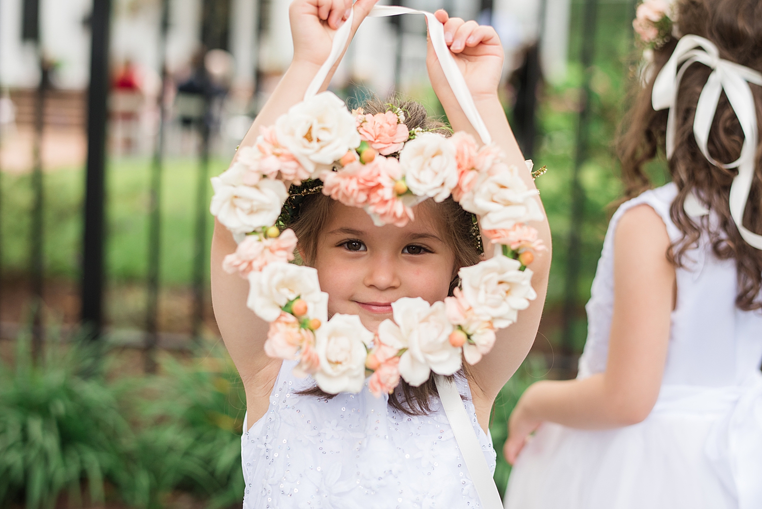 flower girl holds up heart shaped wreath with ivory and blush flowers