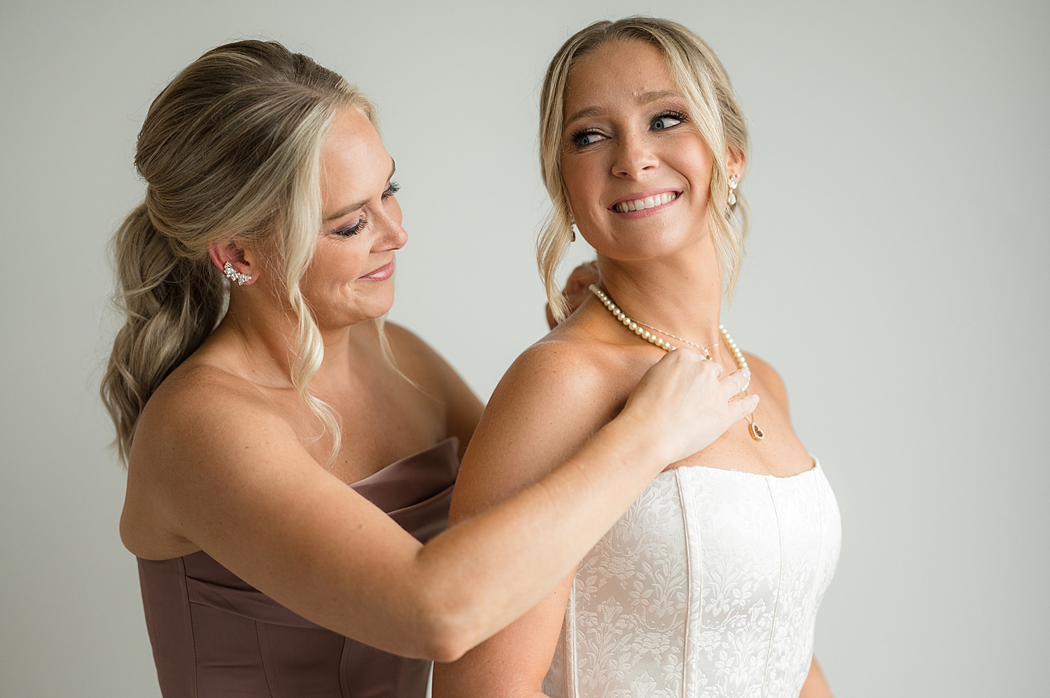 sister helps bride with necklace