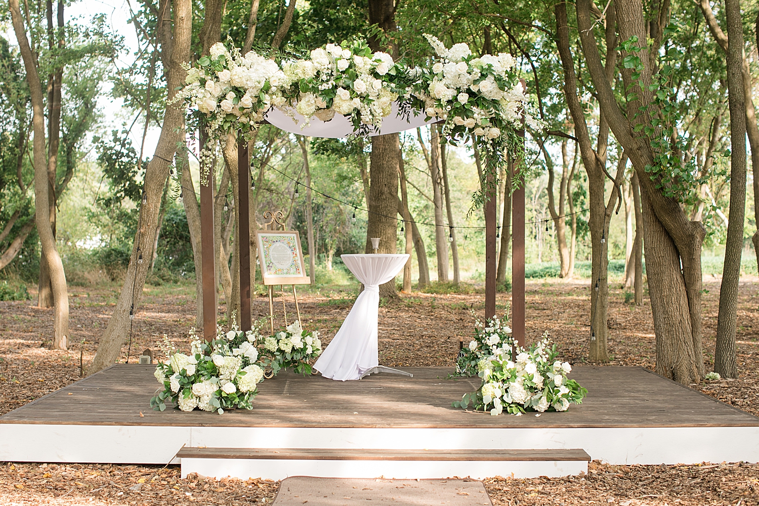 outdoor ceremony space with natural arch and white florals